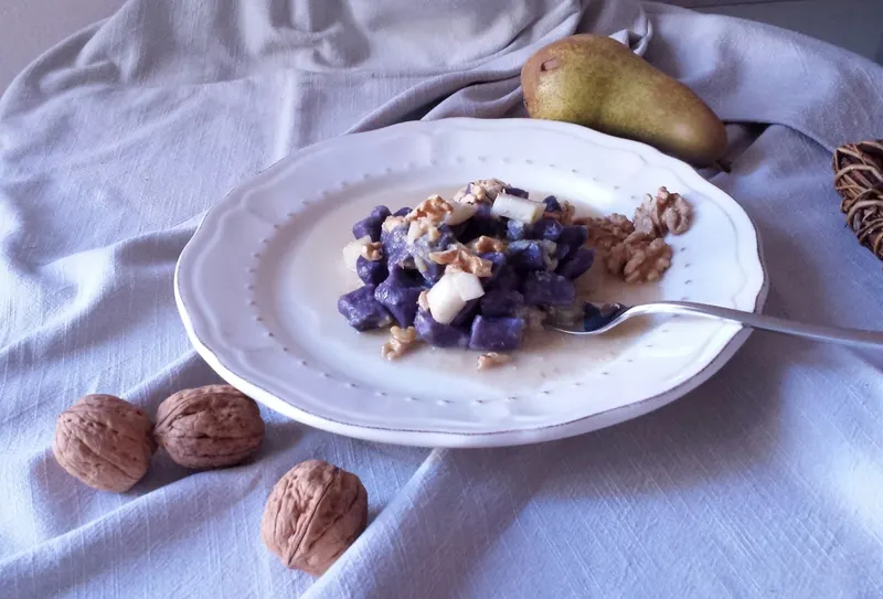 Gnocchetti di patate viola da vicino con pera e noci