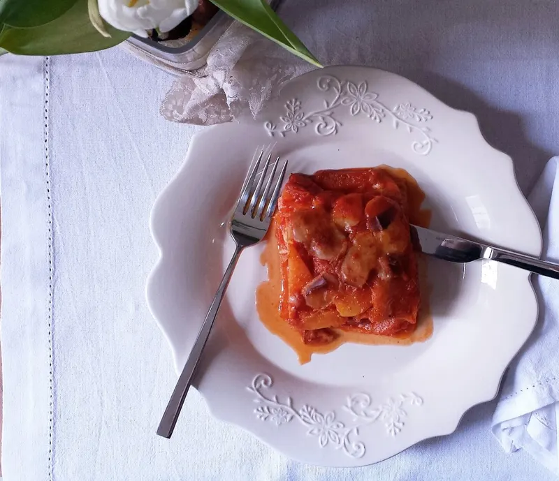 Porzione di parmigiana di zucca con scamorza e sugo di pomodoro