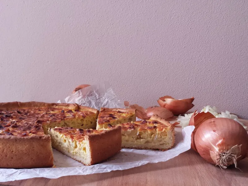 Una fetta di torta salata di cipolle servita tiepida
