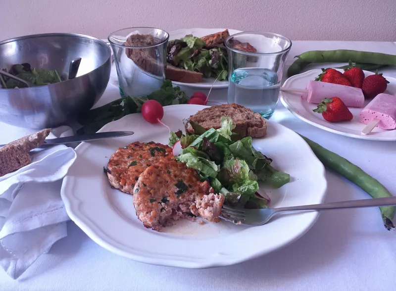 Hamburger di salmone dorati serviti con insalata mista di stagione