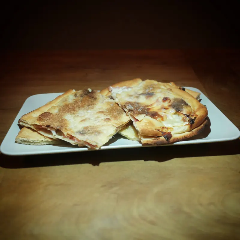 Focaccia di Recco finta appena sfornata, dorata e bucherellata in teglia