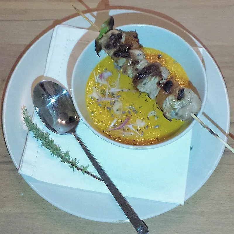 Zuppetta di melone servita nella cocotte accanto agli spiedini di agnello